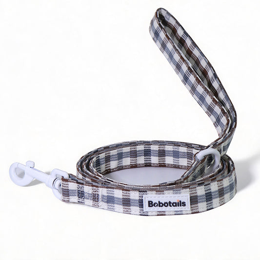 A plaid dog leash with a white clip and white D-rings, featuring a white label with the brand name 'Bobotails'. The leash has a pattern of brown, gray, and white plaid, shown on a clean white background.
