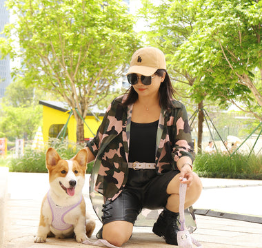 Dog mom outdoors with a Corgi wearing a small dog harness and leash