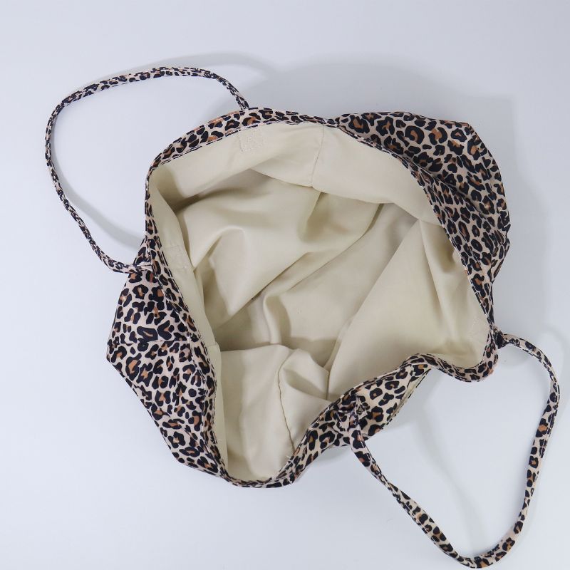 A leopard print shoulder bag with a cream-colored interior lining, shown from a top-down view on a light gray background.