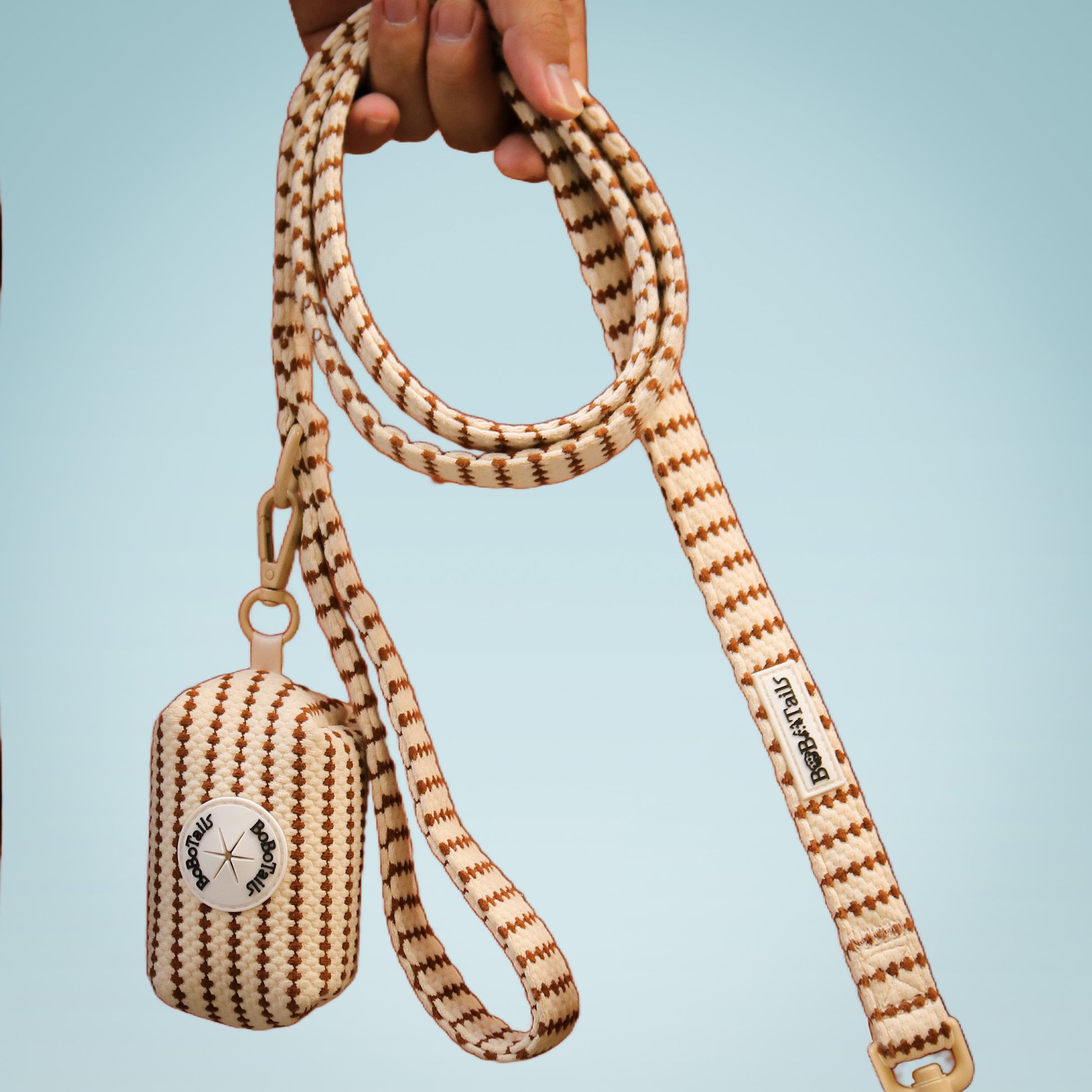 small grain  dog leash with matching pouch held by a hand against a light blue background
